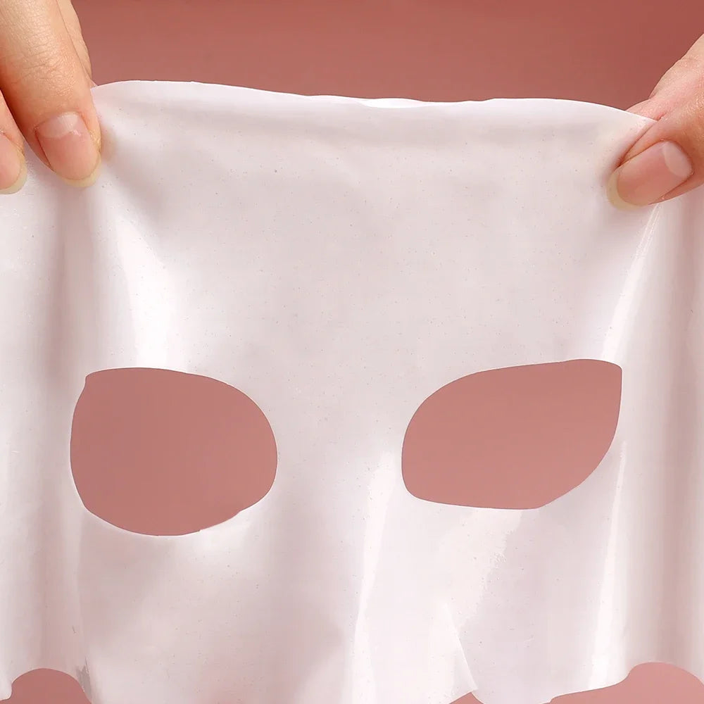 White fabric with two brown patches held by hands against a pink background